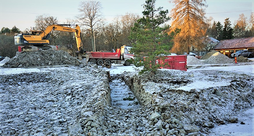 Foto på urgräven rälsbana, stenmassor och en grävmaskin som fyller stenmassor i en lastbil vid Central gruvområdet, Sala Silvergruva